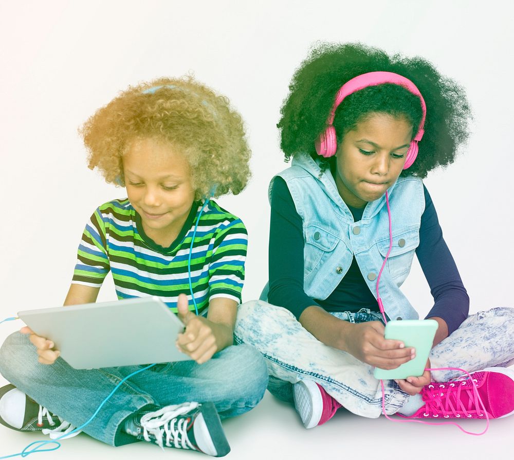Young kids using tablet and mobile to listen to music