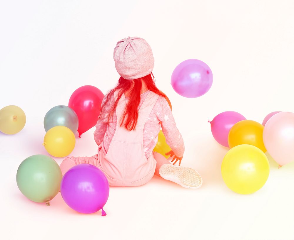 Young girl sitting and playing with balloons