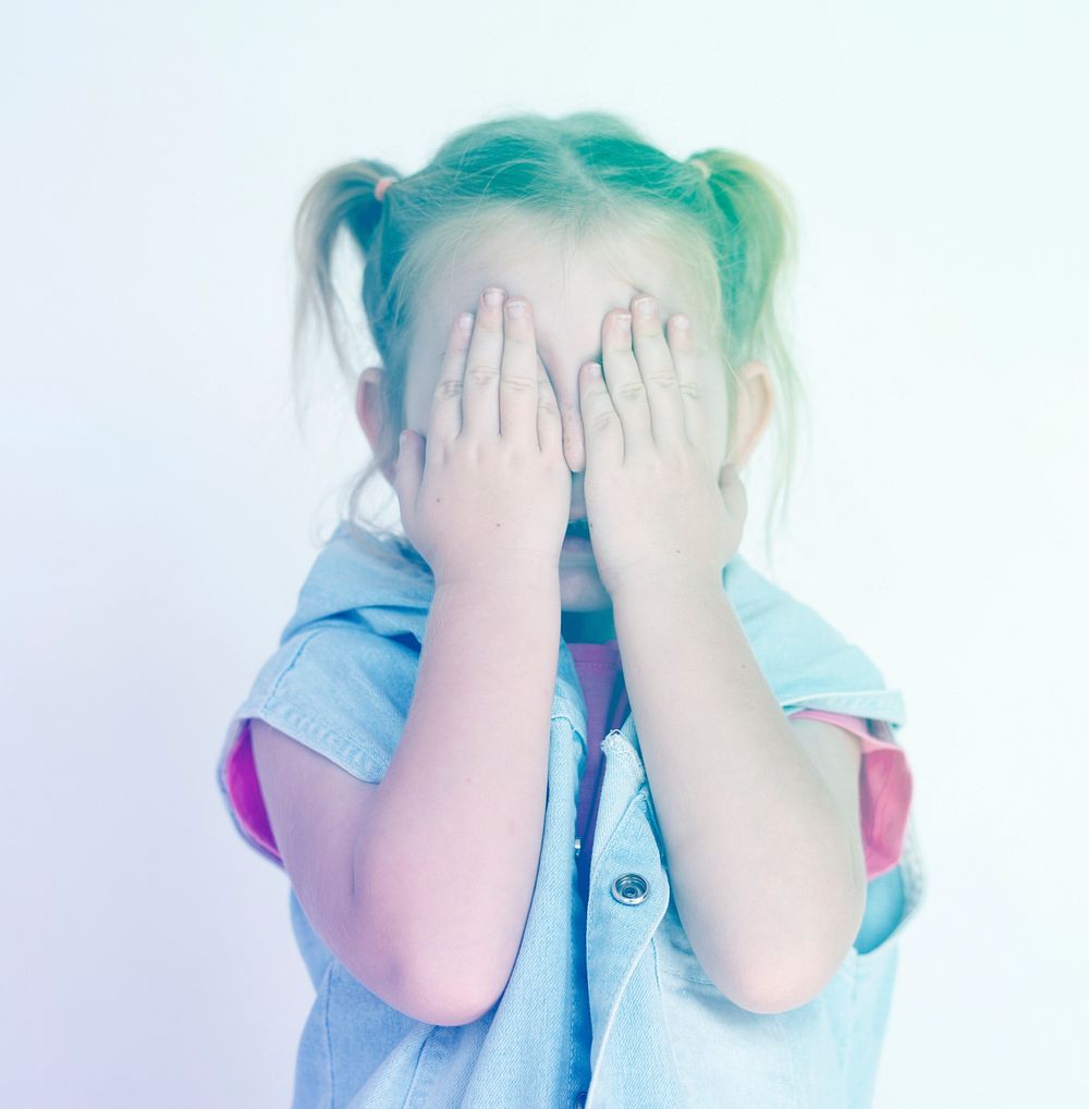 Little girl standing and covering face