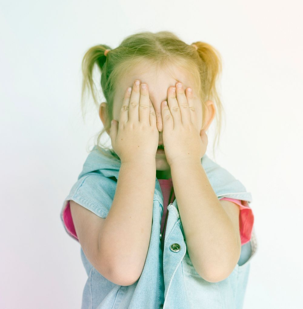 Little girl standing and covering face