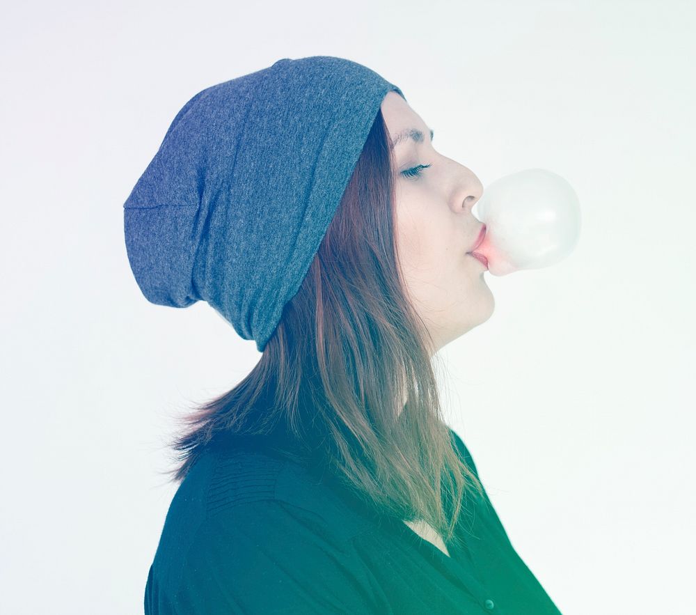 Woman eating and blowing bubblegum on white background