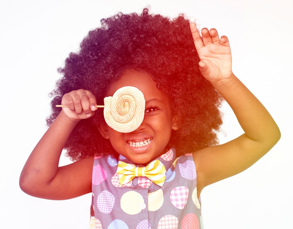 Little girl smiling and make lollipop covering eye