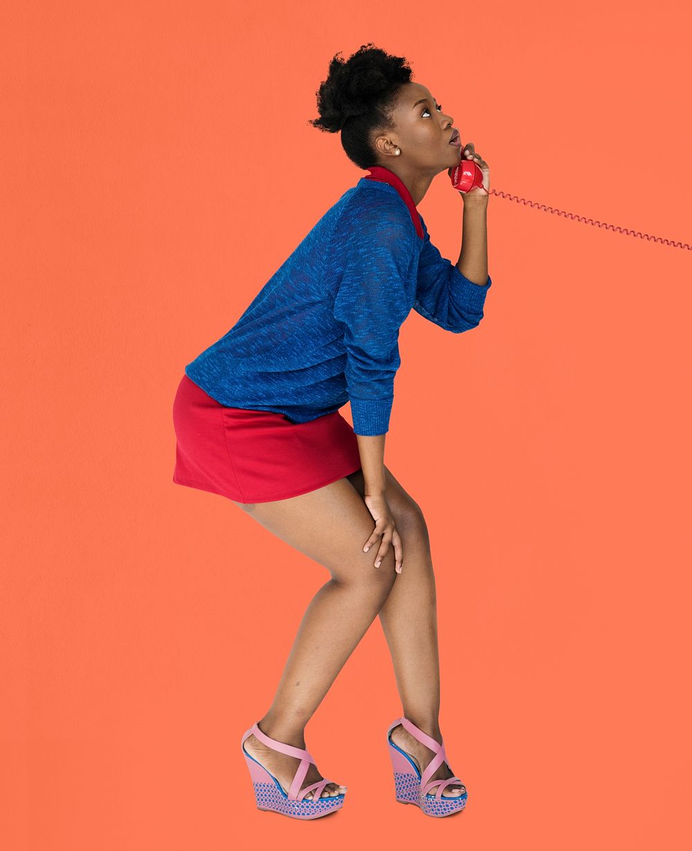 Studio portrait of a young woman bending her knees while talking on the phone