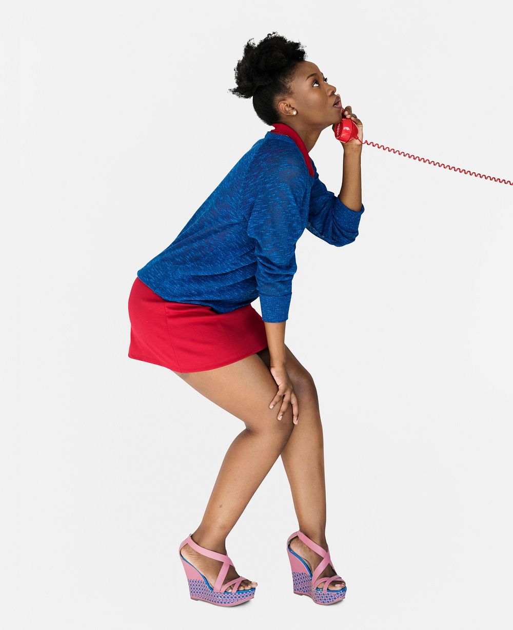 Studio portrait of a young woman bending her knees while talking on the phone