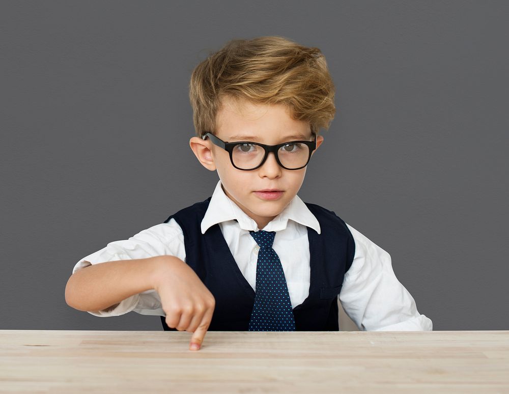 A Caucasian Boy Pointing Wooden Table Background Studio Portrait