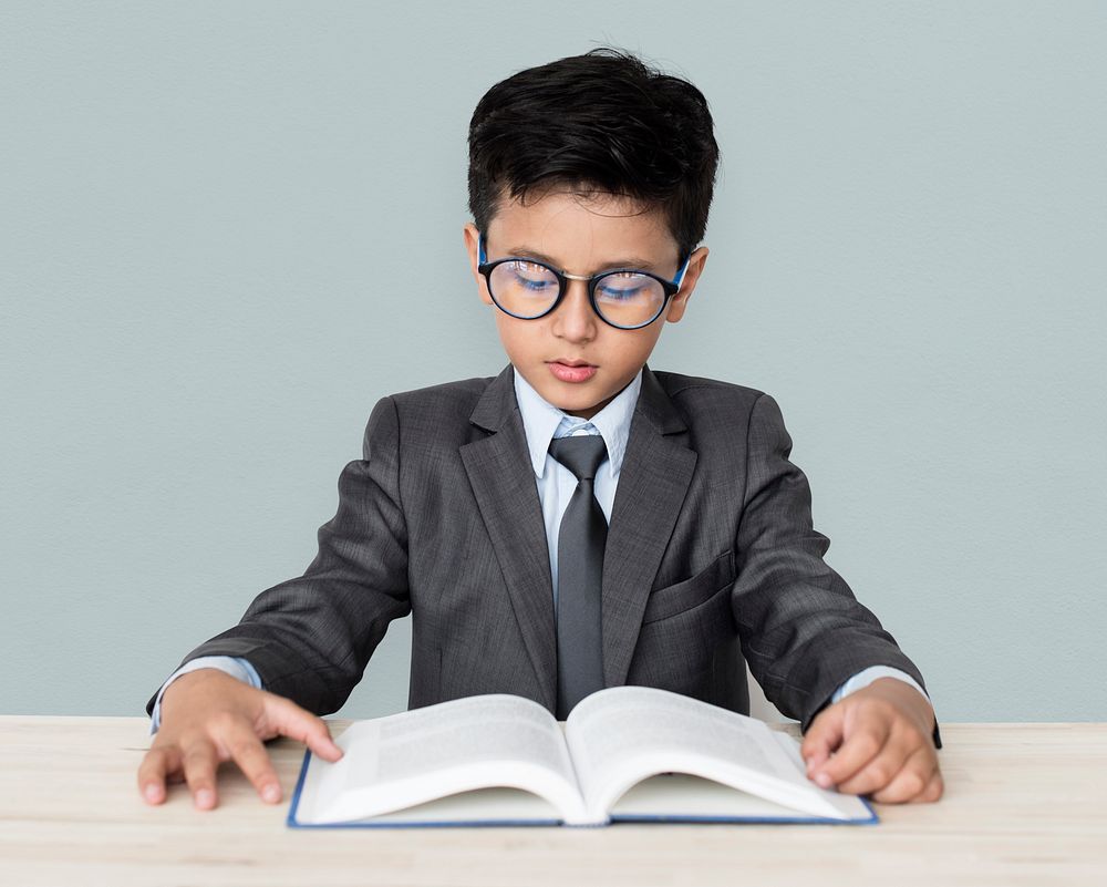 A Caucasian Boy With Glasses Reading Book Background Studio Portrait