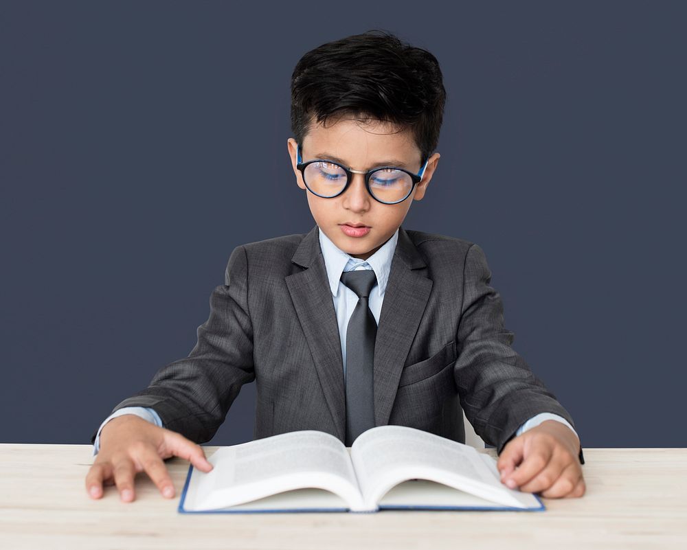 A Caucasian Boy With Glasses Reading Book Background Studio Portrait
