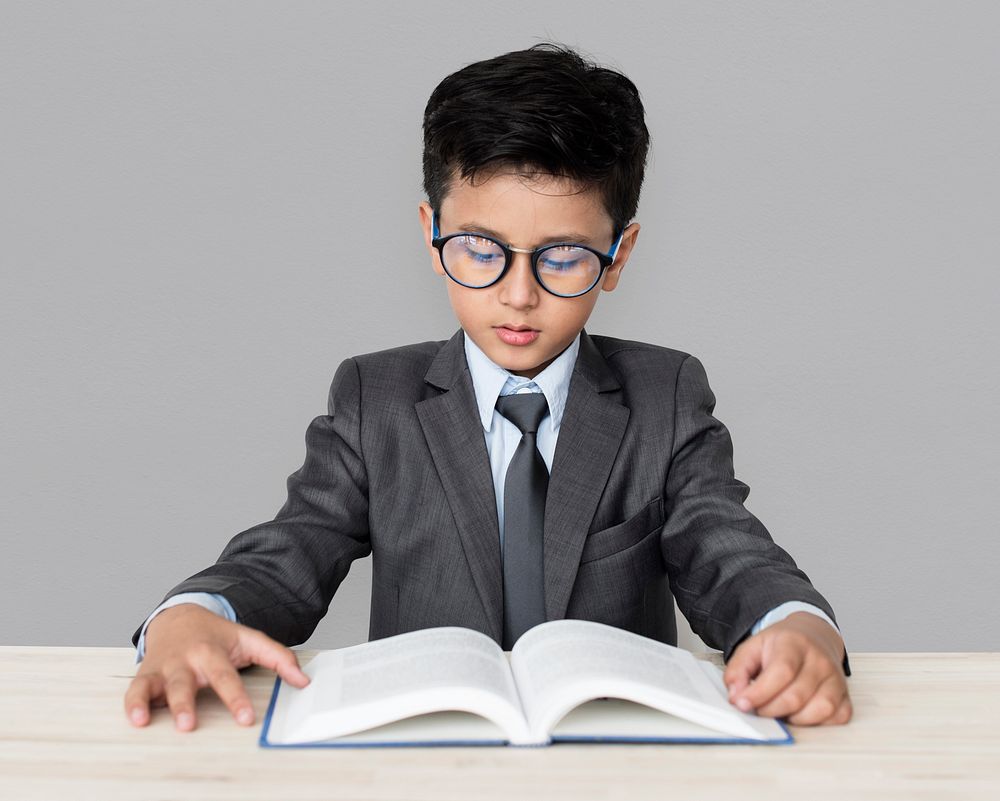 A Caucasian Boy With Glasses Reading Book Background Studio Portrait