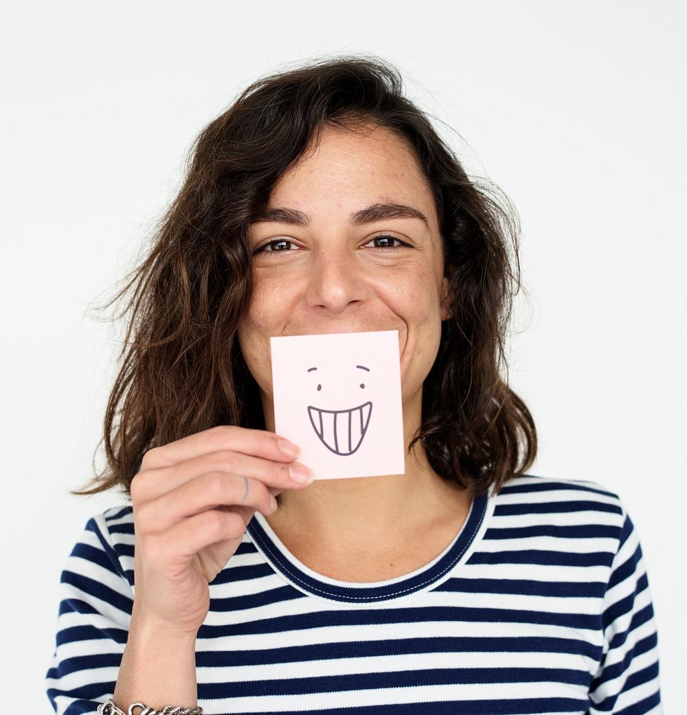 Portrait of a woman holding a smiley drawing to her mouth