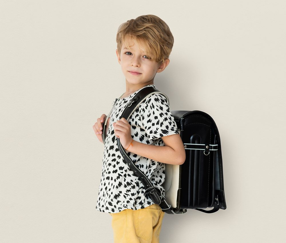 Young blonde boy carrying a backpack portrait