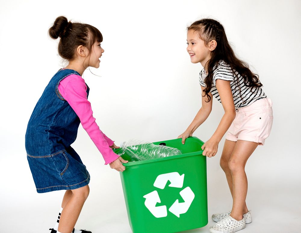Two little girls moving a recycle box