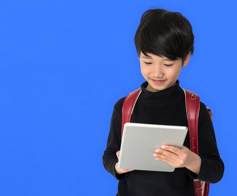 A boy with a backpack and tablet.