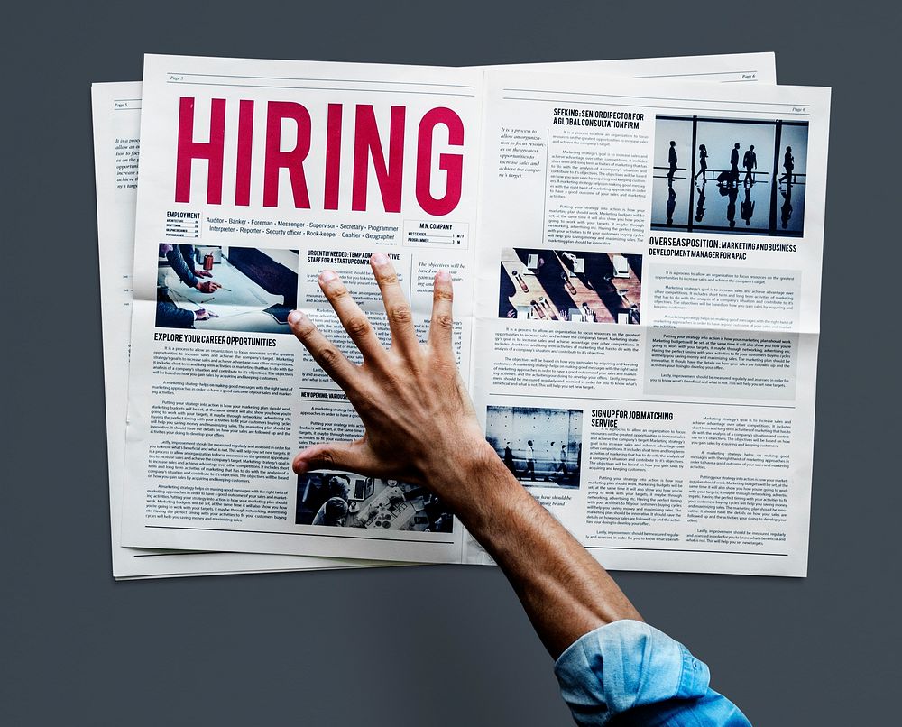 Hand reaching to grab newspaper for hiring job announcement