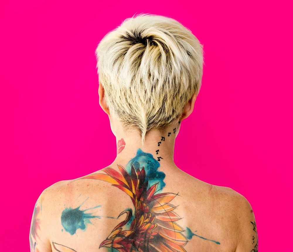 Portrait of a woman showing off her back tattoos