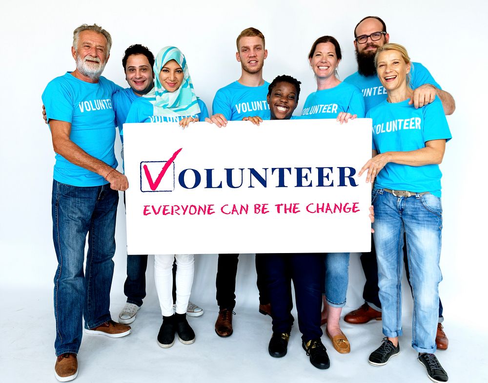 Group of volunteer people smiling and holding charity banner