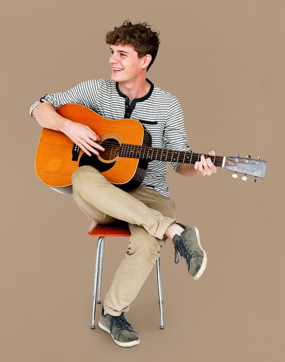 Young Adult Man Sitting Playing Guitar Studio Portrait