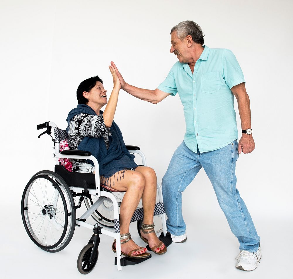 Woman sitting on wheelchair and man standing for photoshoot