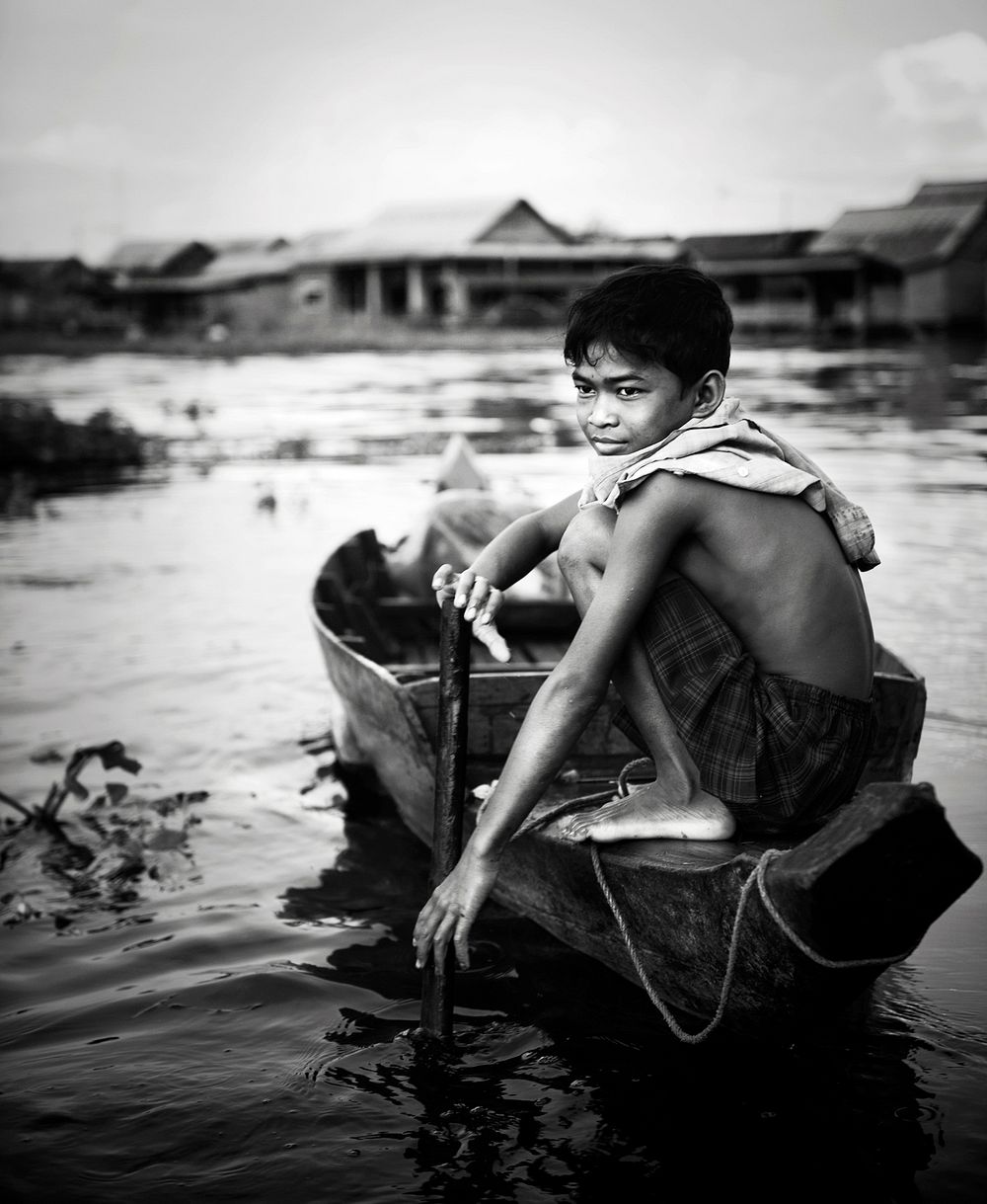Asian young man sitting on the wooden boat in the river grayscale