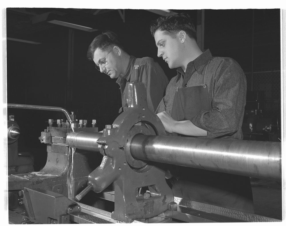 Conversion. Automobiles to 40 mm. anti-aircraft guns. Workers in a former automobile plant machining the firing end of a 40…