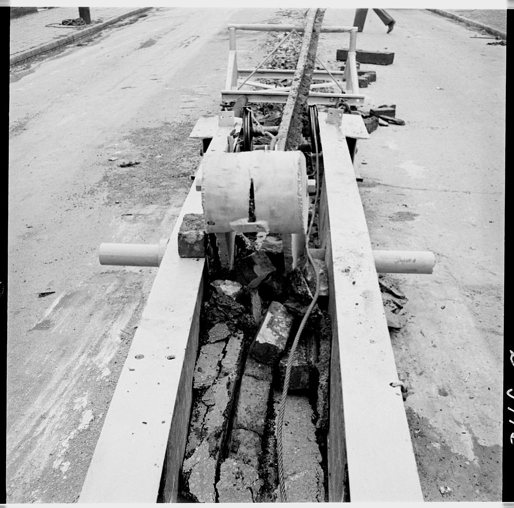 Buried trolley tracks salvaged to aid war program. Recovering buried trolley track to provide scrap for the war effort is an…