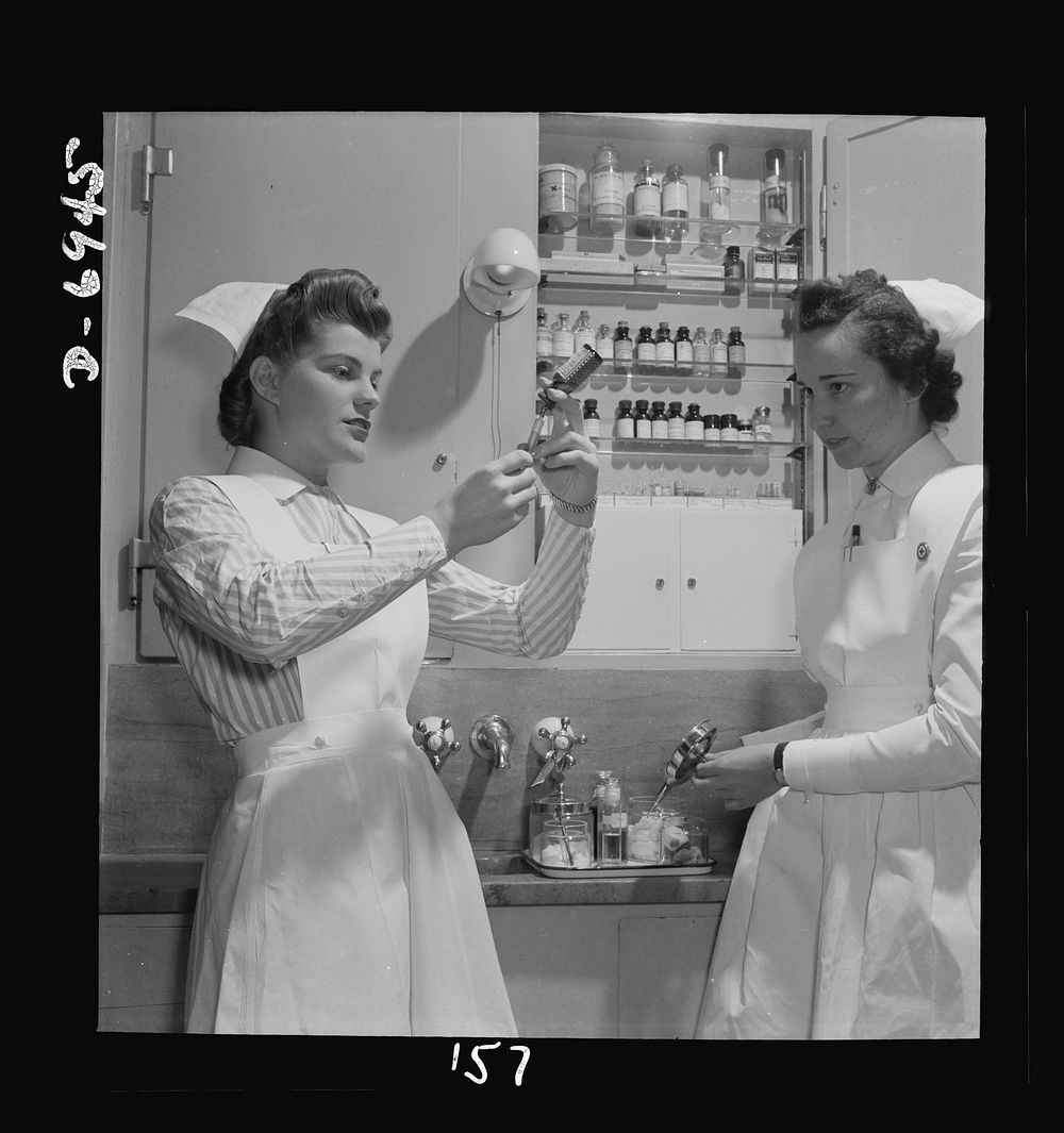 Nurse training. A graduate nurse (right) watches student Susan Petty prepare a hypodermic for a patient. Strict adherence to…