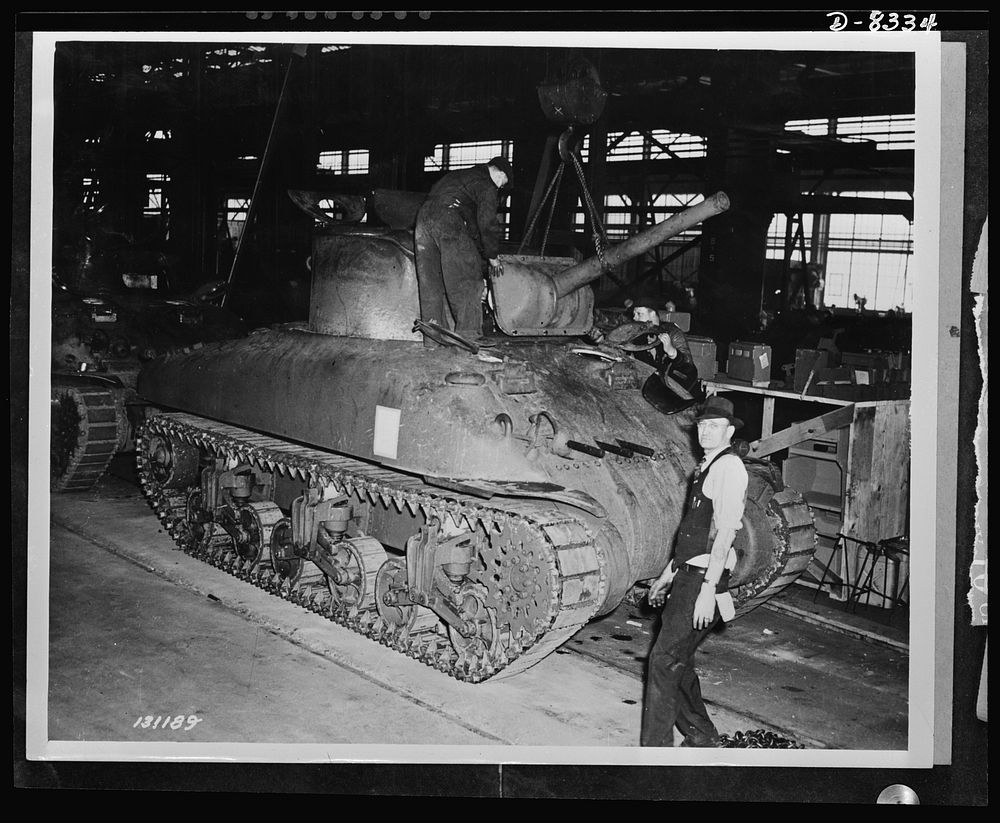 Production. M-4 tanks. Cannon and front turret armored plate are lowered into place on an M-4 tank. Machine guns have…