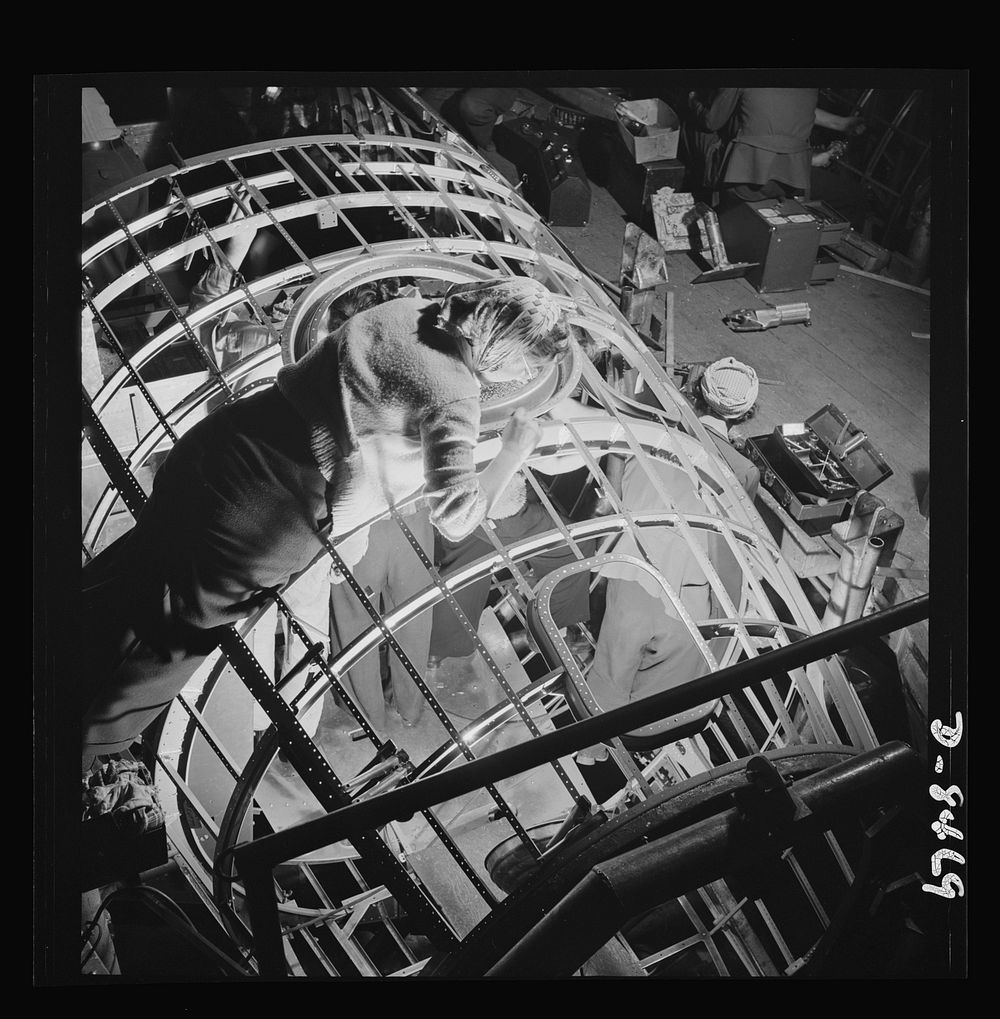 Production. B-17 heavy bomber. A woman worker at the Boeing plant in Seattle helps to complete a fuselage framework for a…
