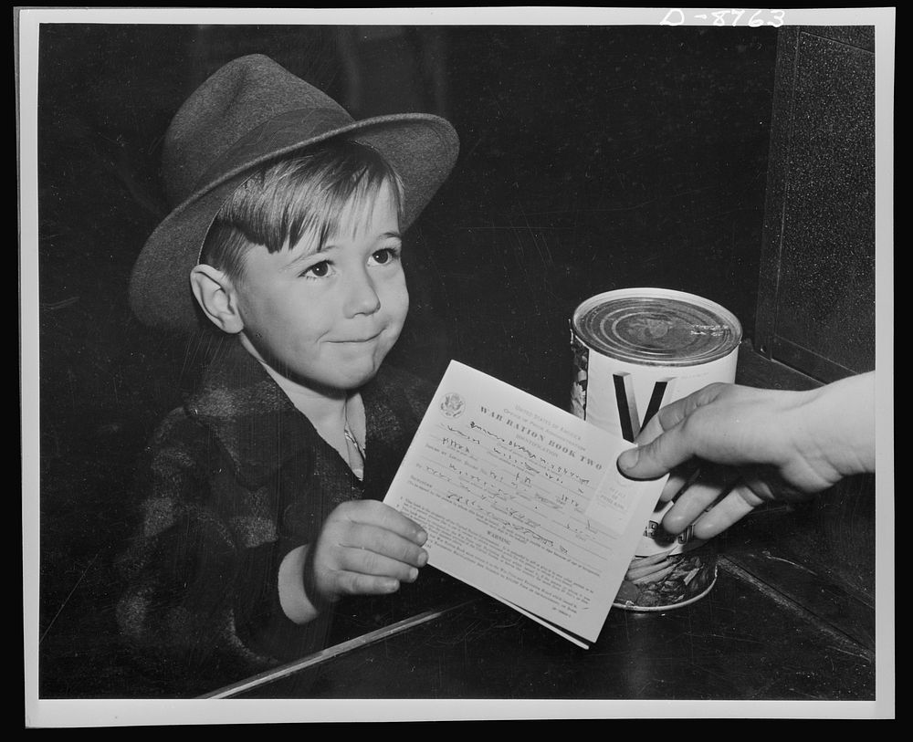 Preparation for point rationing. An eager school boy gets his first experience in using war ration book two. With many…