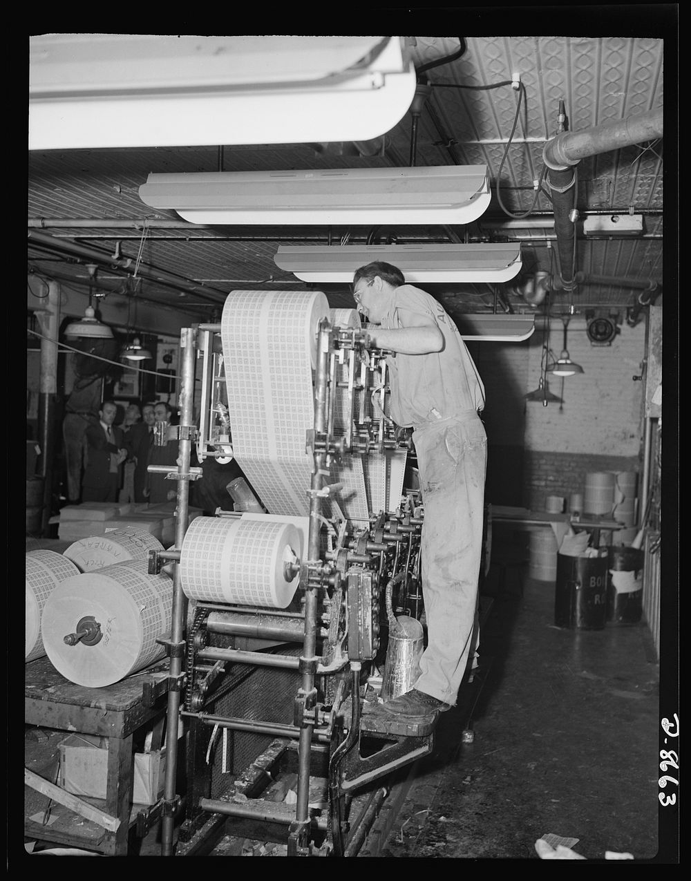 Printing war ration book 2. Another view of the collator with Otto Krantz checking the operation of the collating machinery.…