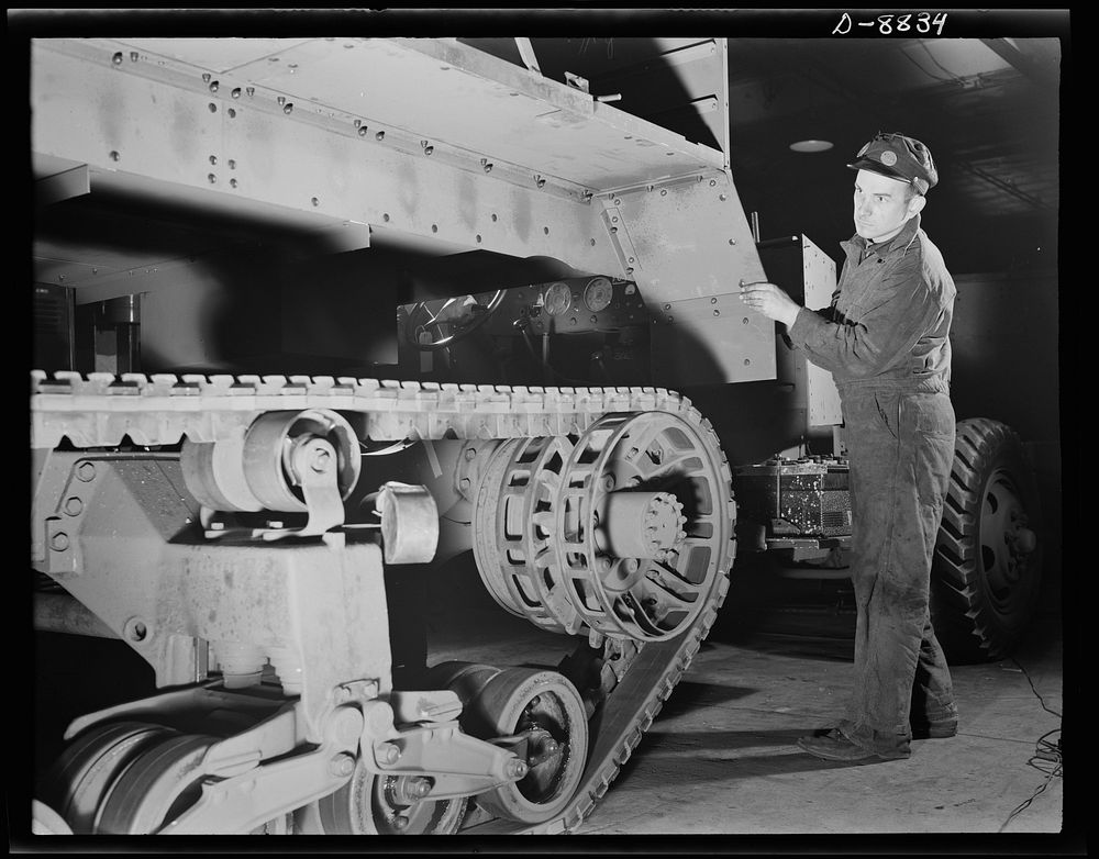 Production. Halftrac armoured cars. A partly-finished halftrac scout car body is lowered on a chassis in an Eastern war…