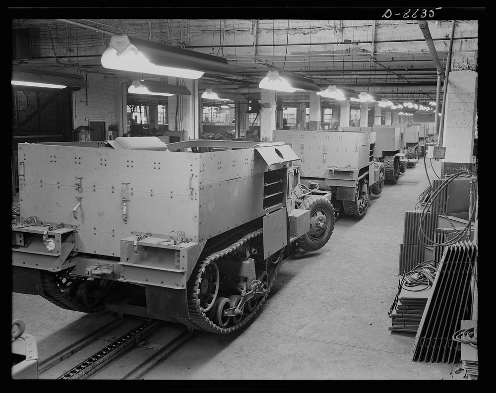 Production. Halftrac armoured cars. Partly finished halftrac scout cars travel along a moving assembly line in a plant…