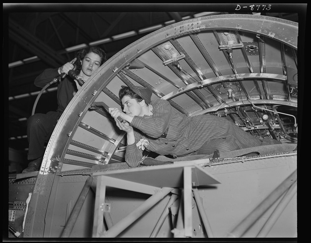 Production. B-24E (Liberator) bombers at Willow Run. A girl team working on a center wing section of a B-24E (Liberator)…