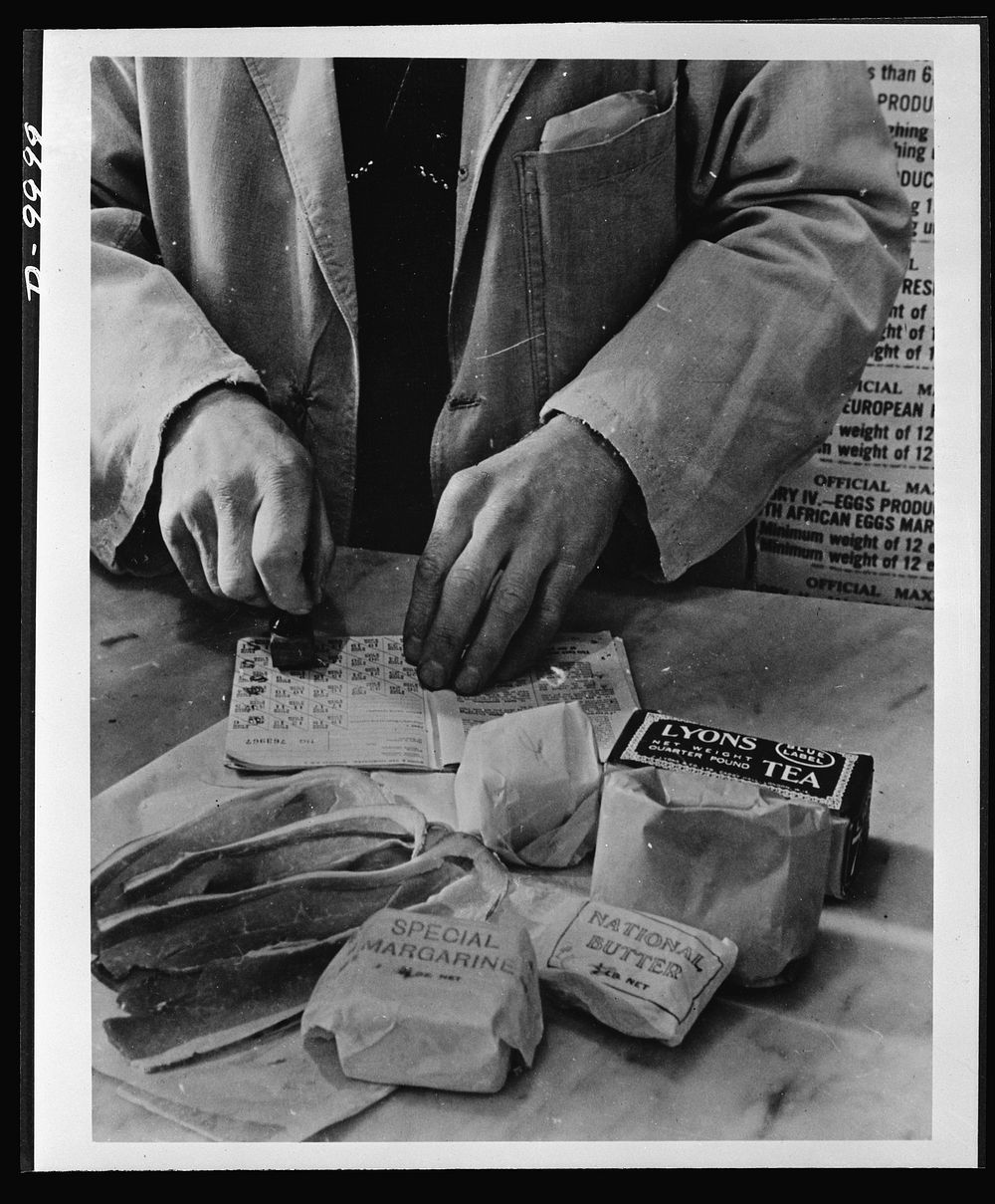 Food in England. A shopkeeper cancels the coupons in a British housewife's ration book for the tea, sugar, cooking fats and…