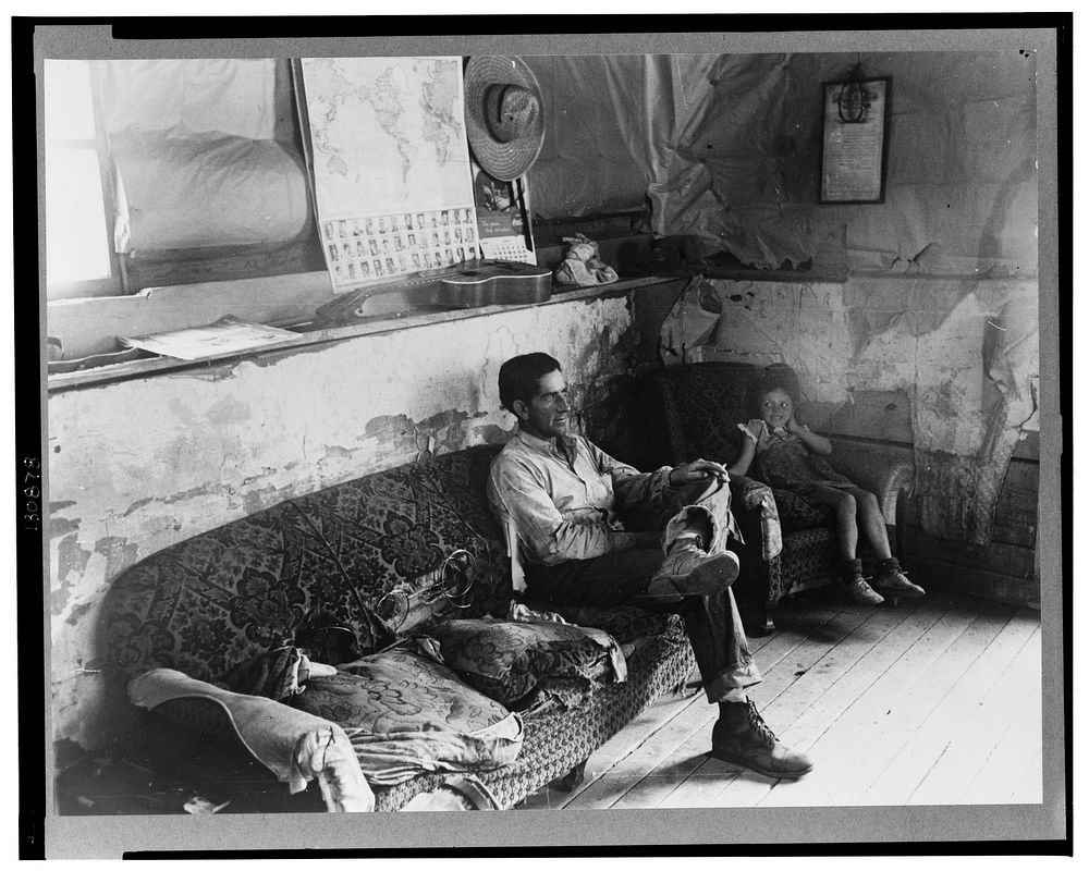 Faro Caudill and his daughter in their dugout home. There hasn't been any cash to buy furniture. Farm expenditures take all…