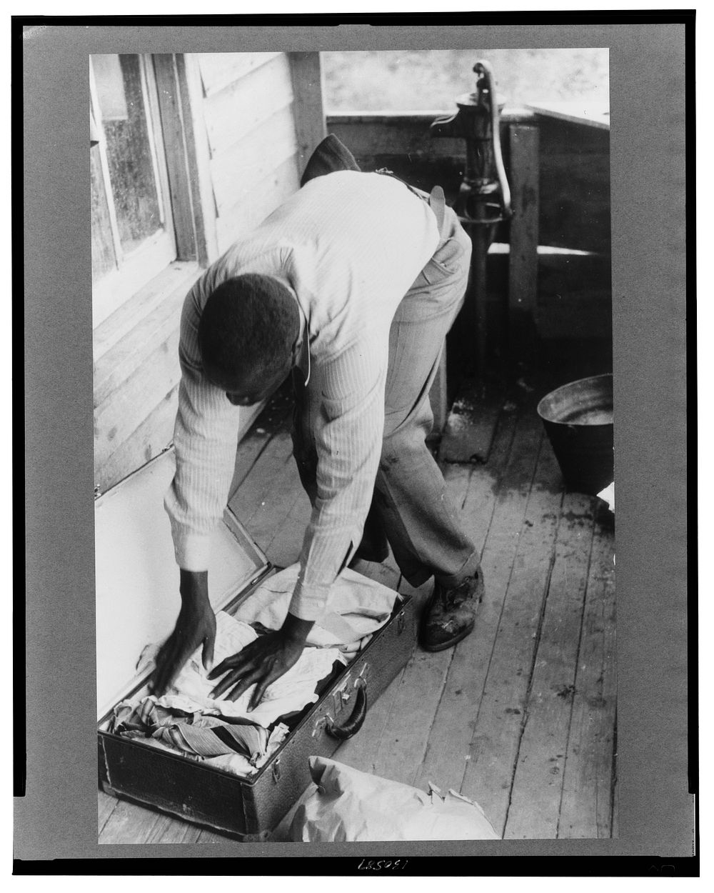 Migrant packing his bag for a trip from Belcross, North Carolina to another job at Onley, Virgin. Sourced from the Library…