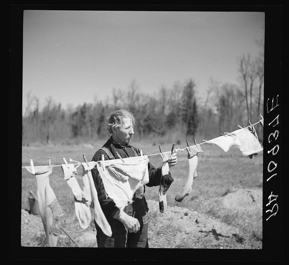 [Untitled photo, possibly related to: John Bastia hanging up his laundry. He is a single shacker in Iron County, Michigan]…