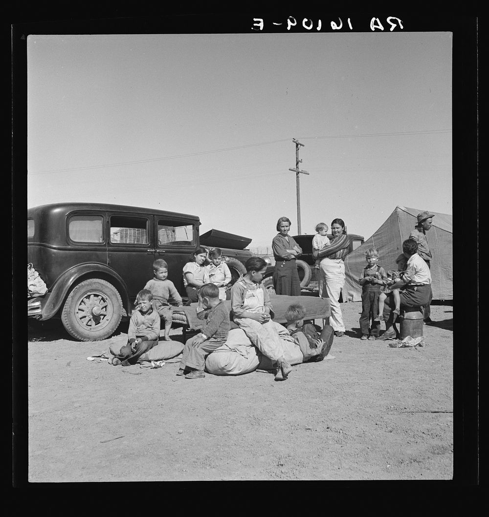 Four families, three of them related with fifteen children, from the Dust Bowl in Texas in an overnight roadside camp near…