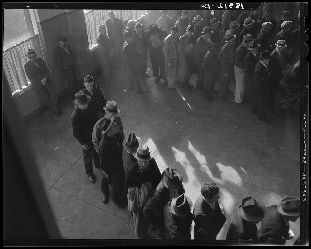 Unemployment benefits aid begins. Line of men inside a division office of the State Employment Service office at San…