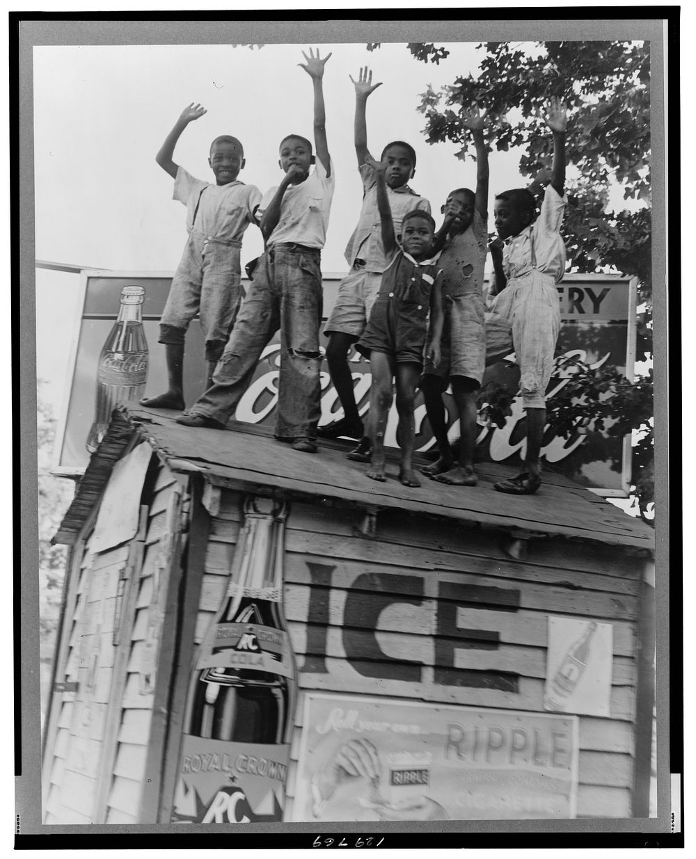 Colored boys playing on top of Coca Cola stand. Little Rock, Arkansas. Sourced from the Library of Congress.