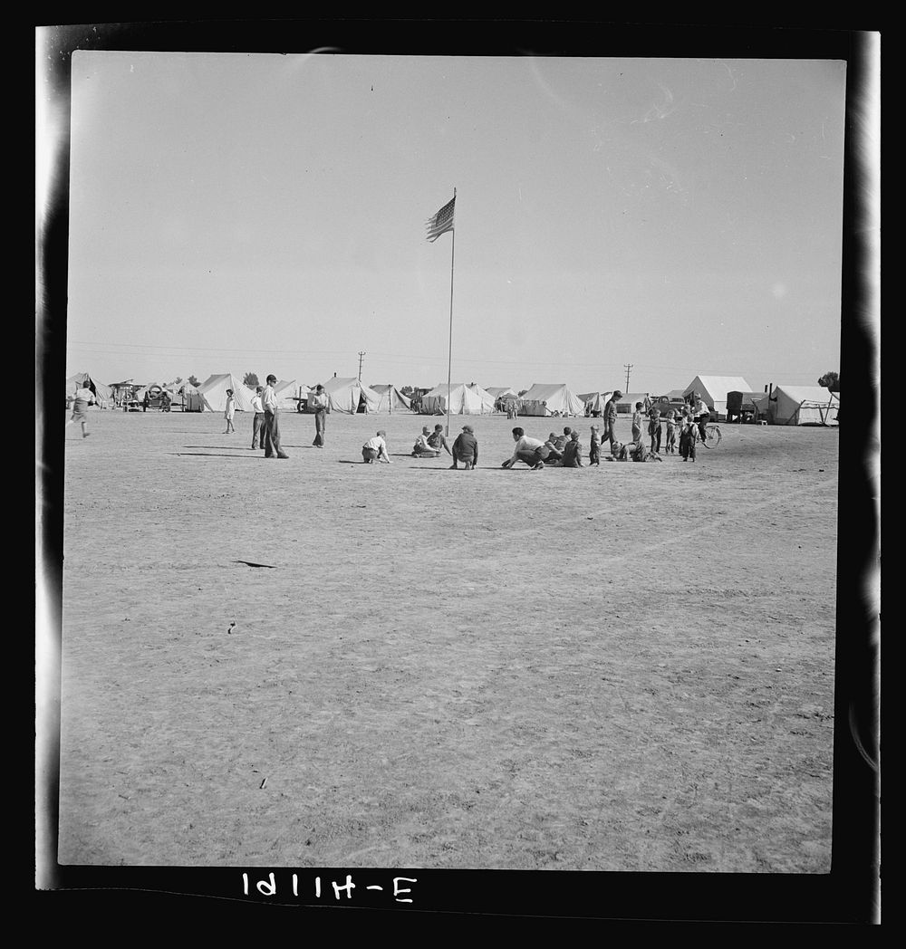 Marble time in Farm Security Administration (FSA) migratory labor camp (emergency.) Plenty of space to play and plenty of…