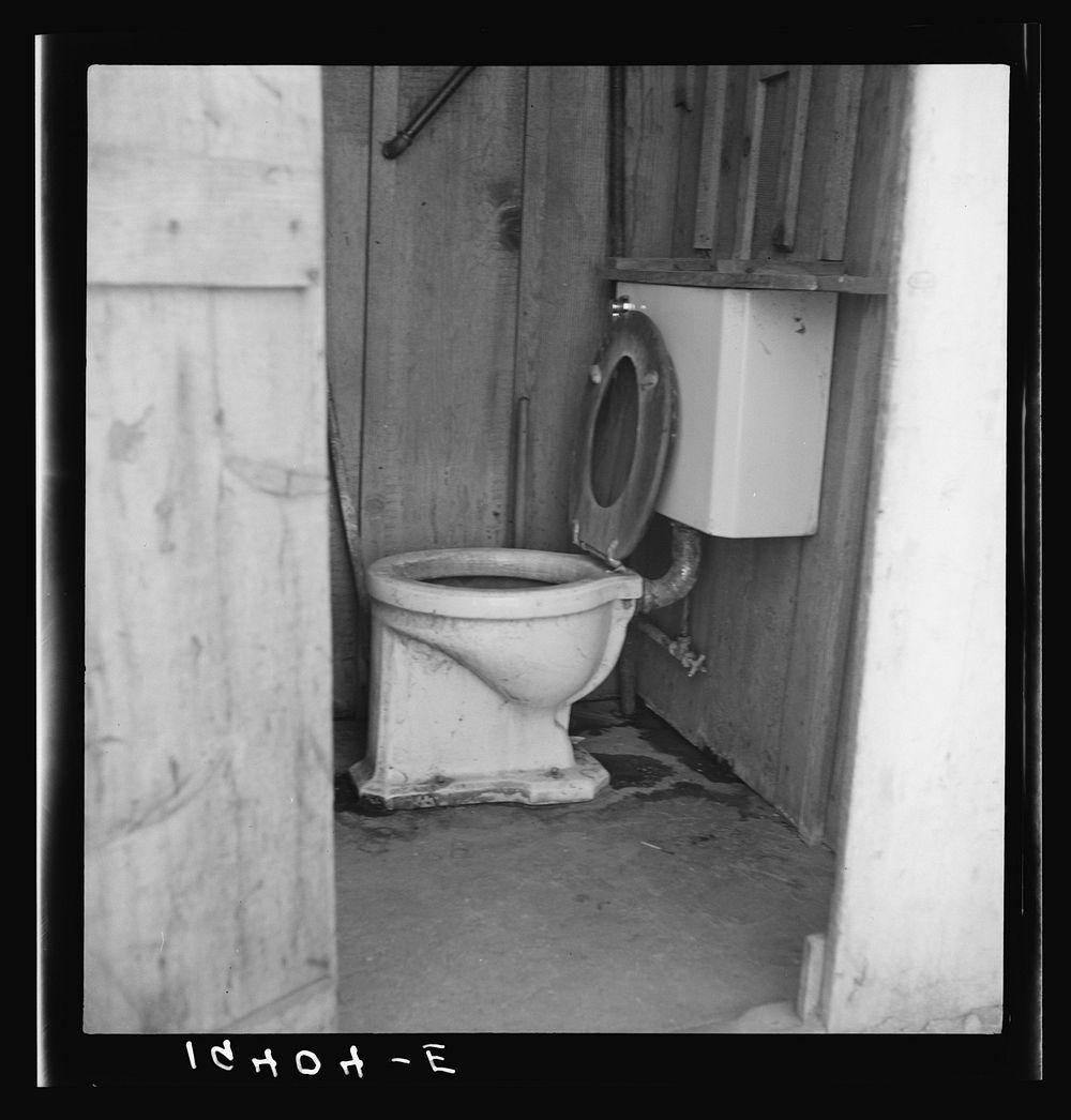 Toilet for ten cabins, men, women and children in auto camp for Arkansawyers, recent migrants to California. Rent for cabins…