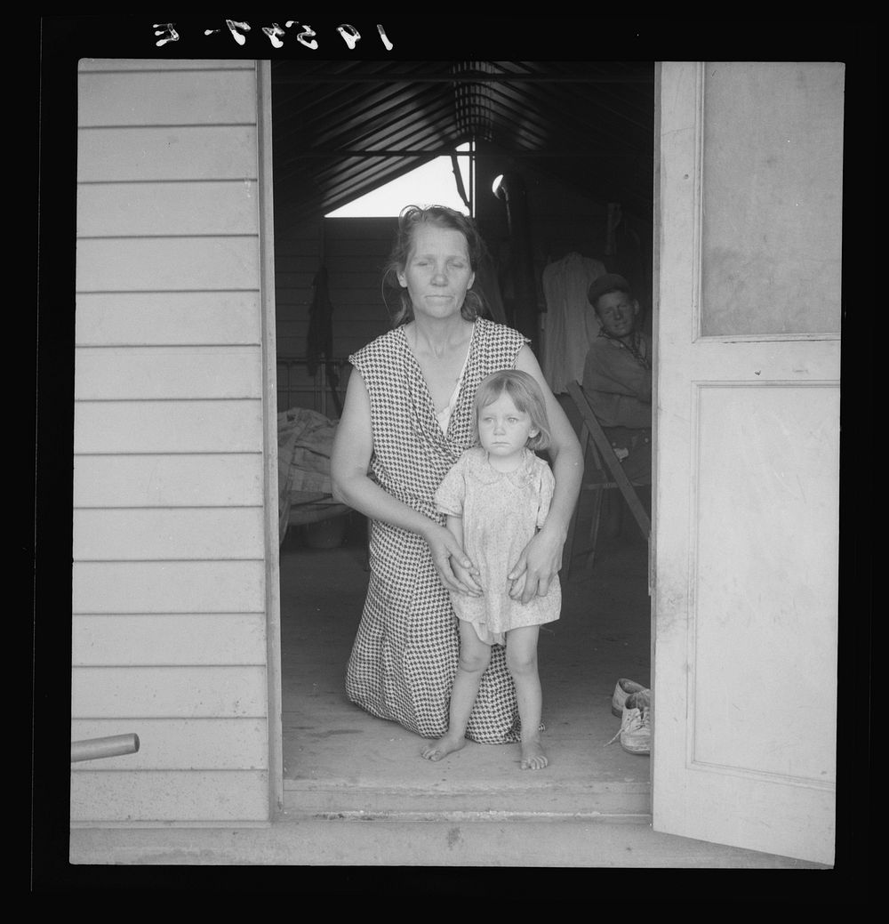 Tulare County, Farm Security Administration (FSA) camp. Migrant mother and child at doorway of steel shelter. Sourced from…