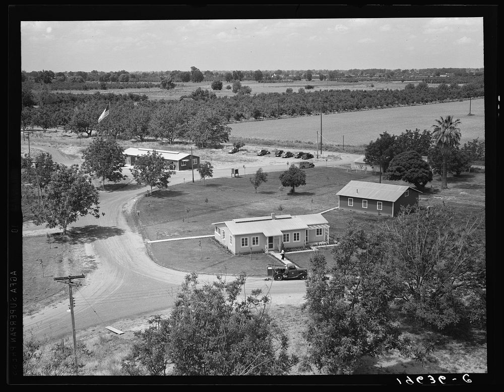 Entrance to camp showing clinic (light building in foreground). Same as 19635. Farmersville, California. Sourced from the…
