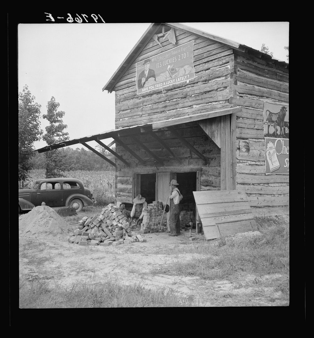 [Untitled photo, possibly related to: Putting in new flues in tobacco barn. The fire burns out the bricks and furnaces have…