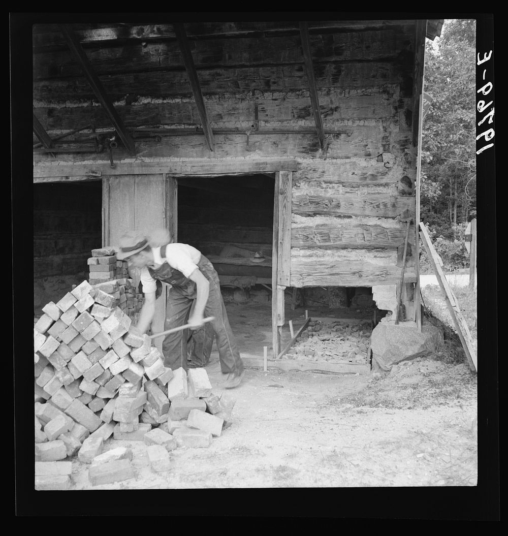 [Untitled photo, possibly related to: Putting in new flues in tobacco barn. The fire burns out the bricks and furnaces have…