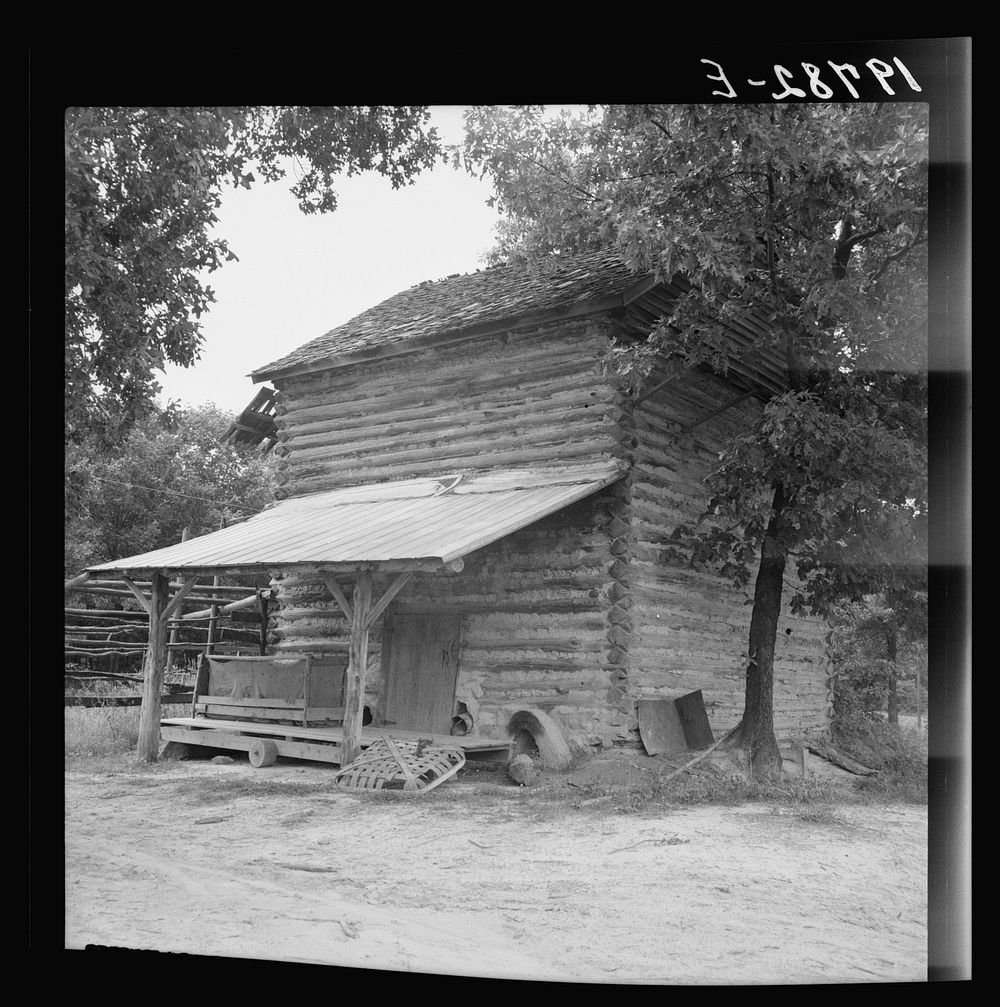 [Untitled photo, possibly related to: Tobacco barn with tobacco sled and vehicle used for conveying tobacco sleds. Person…
