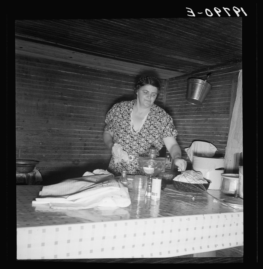 Tobacco sharecropper's wife cleaning up table after washing breakfast dishes. Person County, North Carolina. Sourced from…
