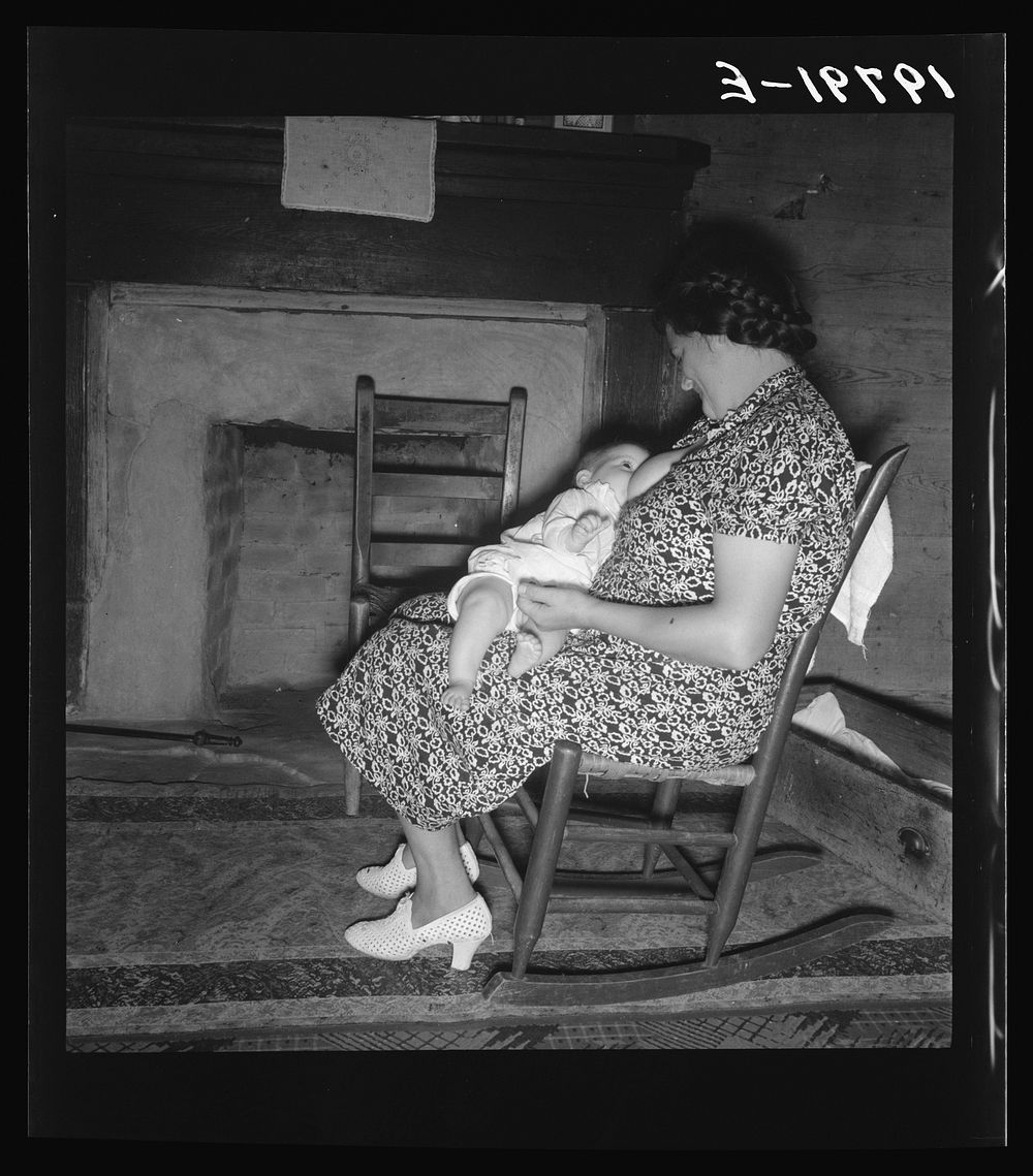 Tobacco sharecropper's wife nurses the baby after washing the dishes and before "straightening up the house." Person County…