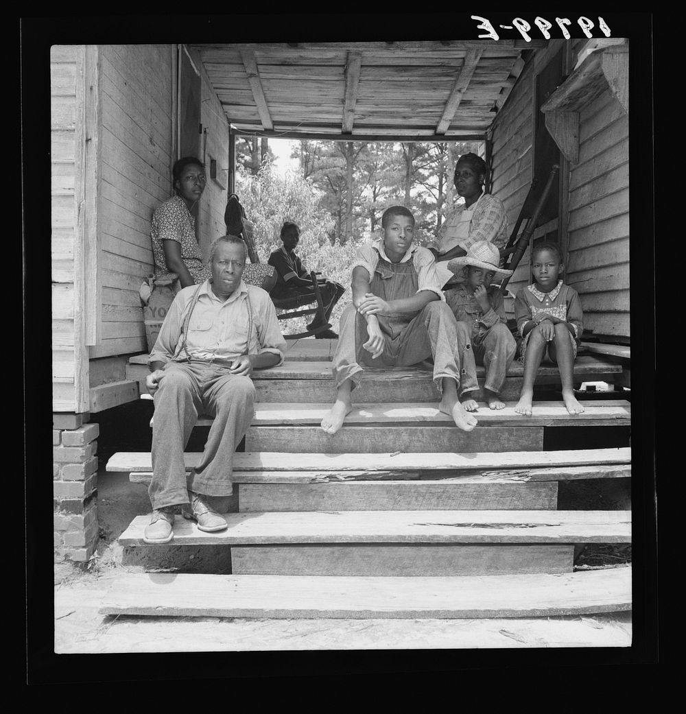 Zollie Lyon,  sharecropper, home from the field for dinner at noontime, with his wife and part of his family. Note dog run.…