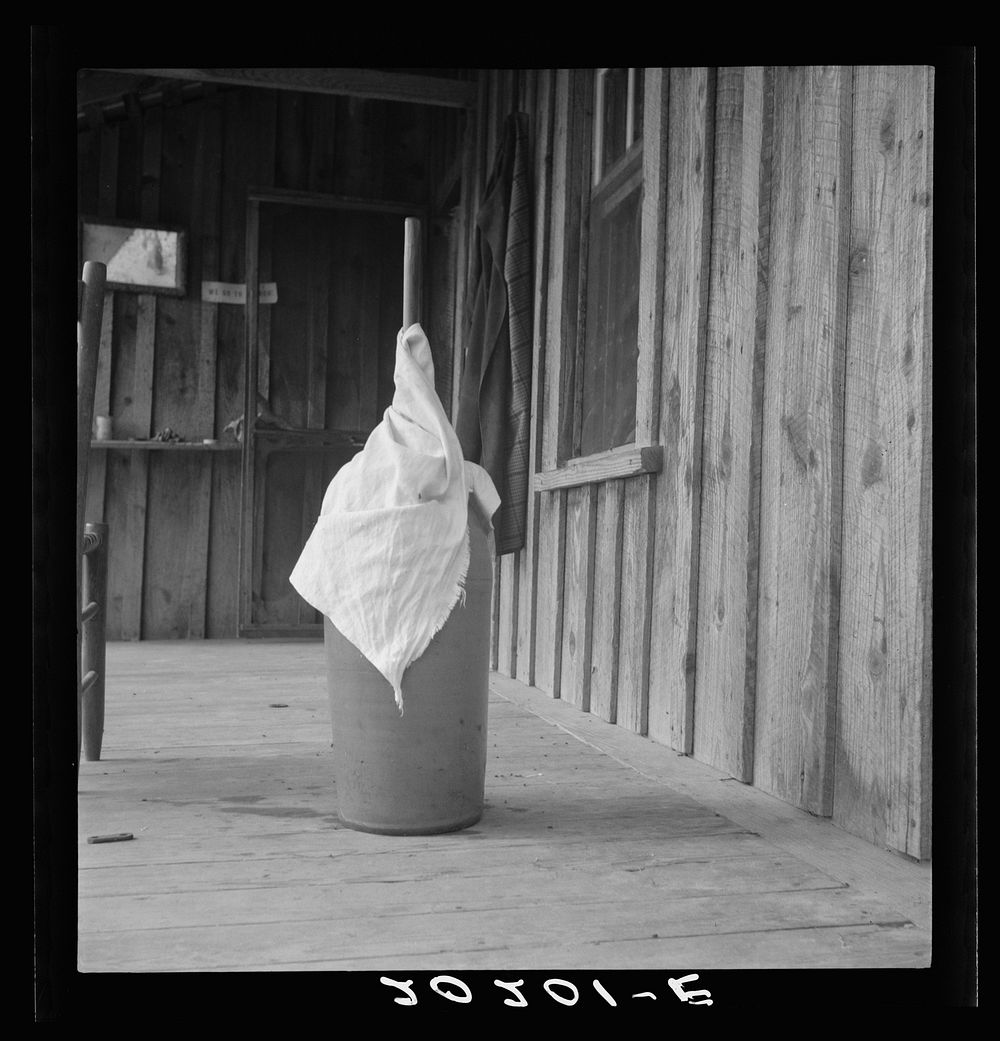 [Untitled photo, possibly related to: Pottery butter churn on porch of  tenant family. The churn is covered with a cloth to…
